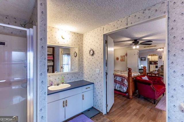 bathroom featuring an enclosed shower, a textured ceiling, vanity, hardwood / wood-style flooring, and ceiling fan