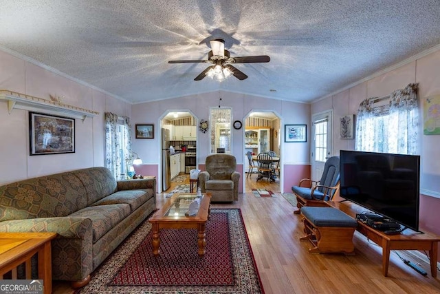 living room featuring crown molding, lofted ceiling, a textured ceiling, and light wood-type flooring