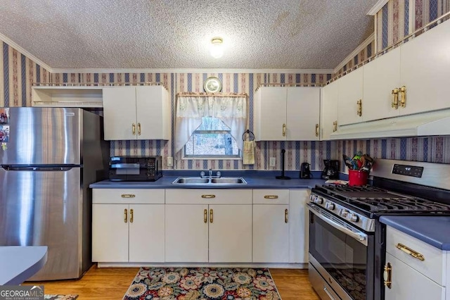 kitchen featuring sink, crown molding, white cabinetry, stainless steel appliances, and a textured ceiling