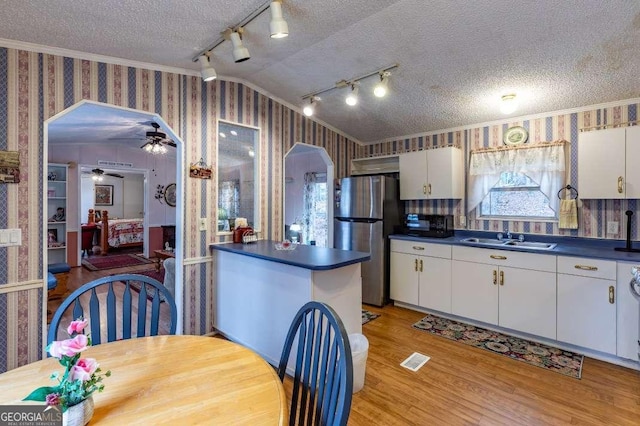 kitchen with stainless steel refrigerator, white cabinetry, sink, crown molding, and a textured ceiling