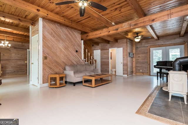 living room with stairs, beam ceiling, wooden walls, wooden ceiling, and ceiling fan with notable chandelier