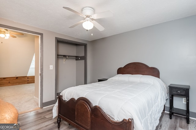 bedroom with a textured ceiling, a ceiling fan, a closet, and wood finished floors