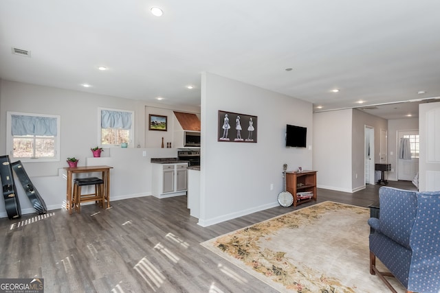 living room with plenty of natural light, visible vents, and wood finished floors