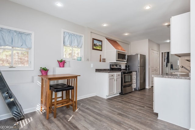 kitchen featuring appliances with stainless steel finishes, dark wood-type flooring, a sink, and white cabinetry