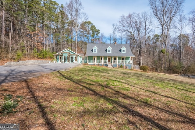 cape cod-style house featuring a front yard and covered porch