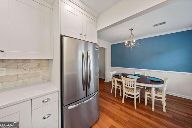 kitchen with light hardwood / wood-style flooring, ornamental molding, stainless steel refrigerator, and white cabinets