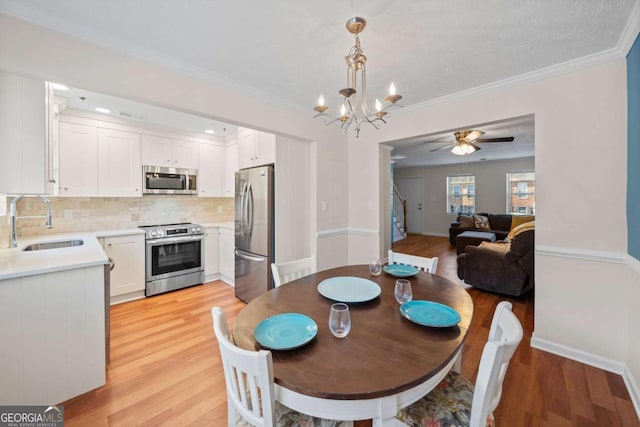 dining space with sink, crown molding, and light hardwood / wood-style floors