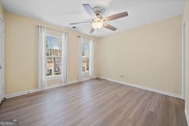 empty room with ceiling fan and light hardwood / wood-style flooring