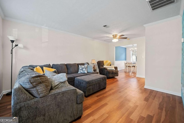 living room with ceiling fan with notable chandelier, ornamental molding, and hardwood / wood-style floors