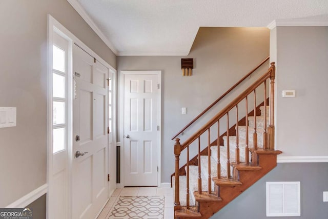 tiled entrance foyer with ornamental molding and a textured ceiling