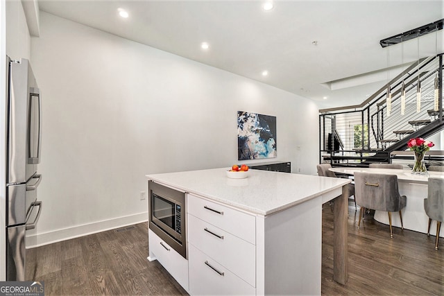 kitchen with dark wood-type flooring, a breakfast bar, a center island, stainless steel appliances, and white cabinets