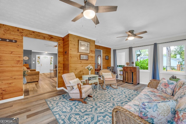 living room with crown molding, hardwood / wood-style floors, a textured ceiling, and wood walls