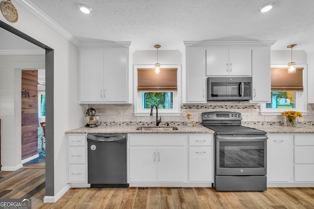 kitchen with pendant lighting, appliances with stainless steel finishes, sink, and white cabinets