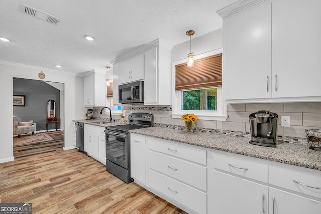 kitchen with decorative light fixtures, sink, white cabinets, stainless steel appliances, and light hardwood / wood-style flooring