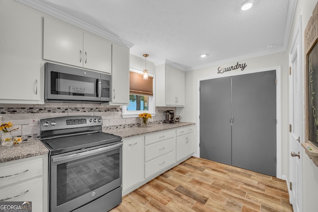 kitchen featuring pendant lighting, white cabinetry, stainless steel appliances, and light hardwood / wood-style floors