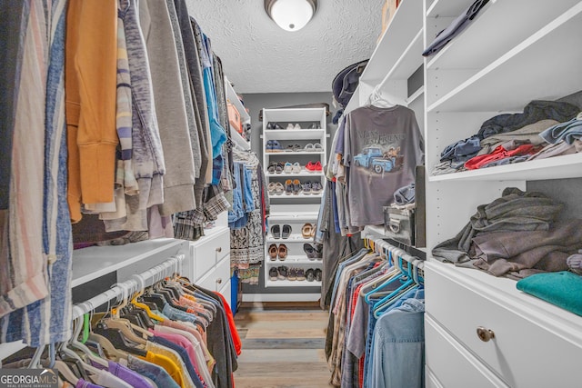 walk in closet with light hardwood / wood-style floors