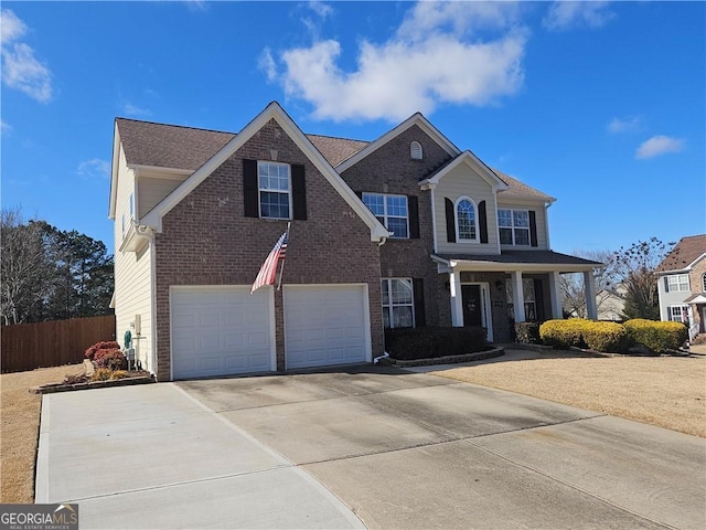 traditional-style home featuring a garage, brick siding, concrete driveway, and fence