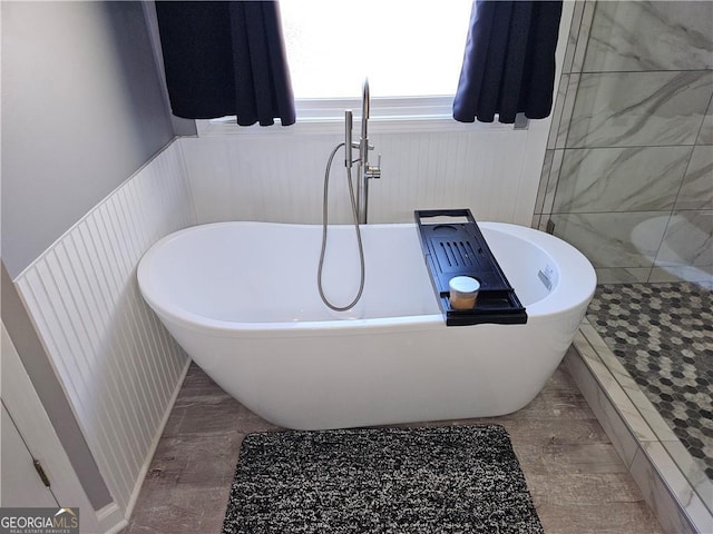 full bath with a wainscoted wall, a soaking tub, and a tile shower