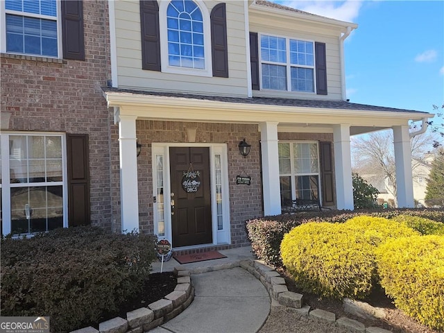 property entrance featuring brick siding and a porch