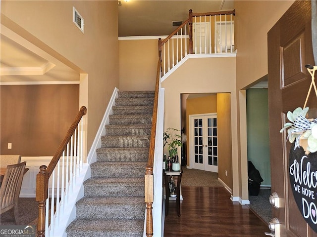 stairs with visible vents, crown molding, baseboards, and wood finished floors