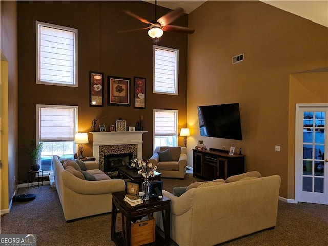 living area with a glass covered fireplace, a healthy amount of sunlight, ceiling fan, and carpet floors