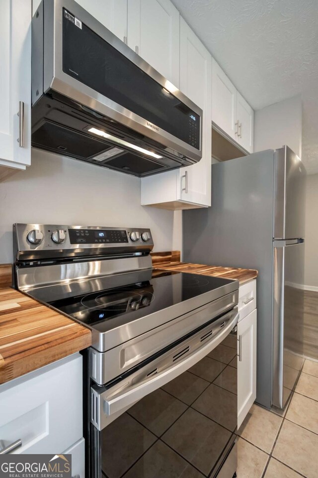 100 Downing Way Unit E, Athens, GA 30606 - kitchen with stainless steel appliances, light tile patterned floors, white cabinets, and wood counters
