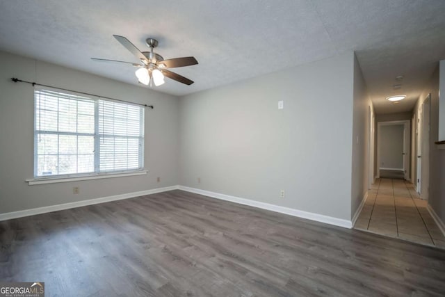 empty room featuring dark wood-type flooring, ceiling fan, and a textured ceiling