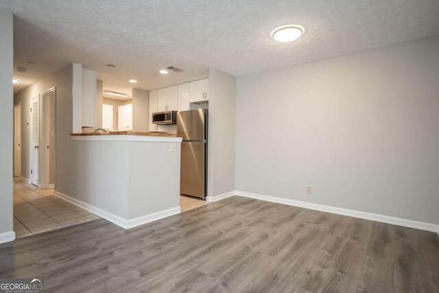 100 Downing Way Unit E, Athens, GA 30606 - kitchen featuring a textured ceiling, light hardwood / wood-style flooring, appliances with stainless steel finishes, kitchen peninsula, and white cabinets