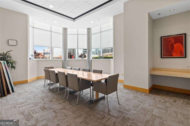 dining space with a tray ceiling and carpet flooring