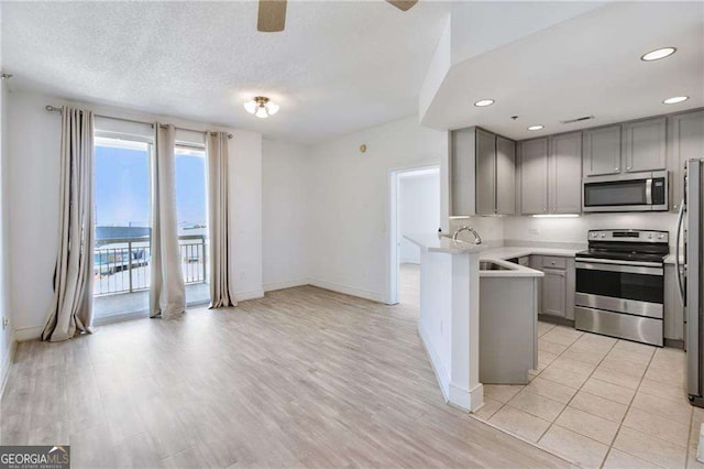 kitchen featuring gray cabinets, appliances with stainless steel finishes, sink, kitchen peninsula, and a textured ceiling