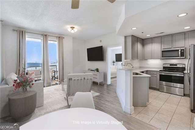 kitchen featuring sink, gray cabinetry, kitchen peninsula, stainless steel appliances, and a textured ceiling