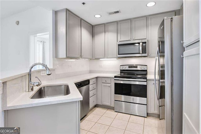 kitchen with stainless steel appliances, sink, decorative backsplash, and gray cabinetry