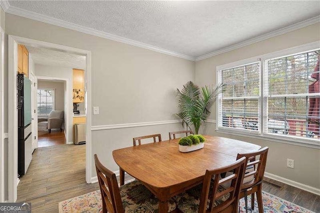 dining room with crown molding, light hardwood / wood-style floors, and a textured ceiling