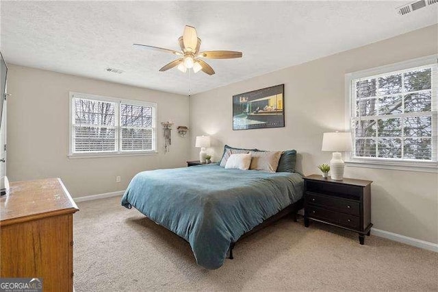 bedroom with light carpet, ceiling fan, multiple windows, and a textured ceiling