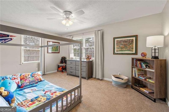 bedroom with ceiling fan, light colored carpet, and a textured ceiling