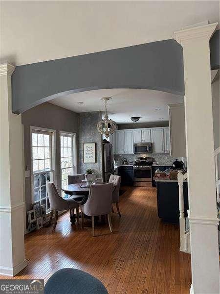 dining space with dark wood-type flooring and an inviting chandelier