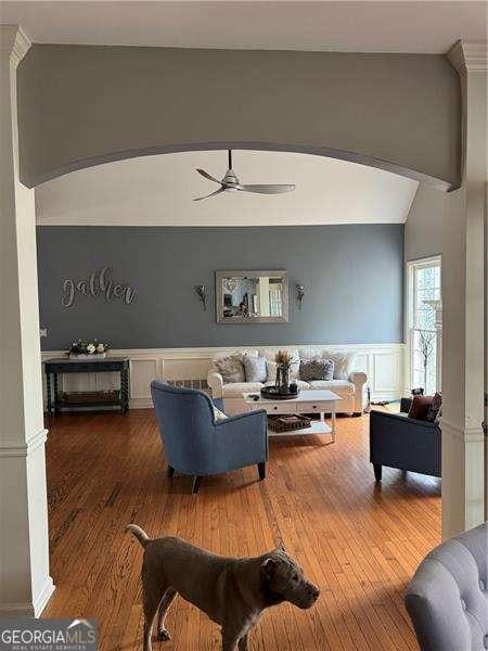 living room featuring lofted ceiling, hardwood / wood-style floors, ceiling fan, and ornate columns