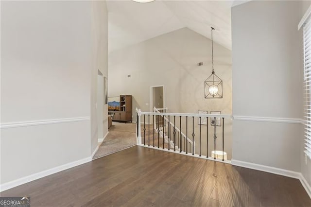 hallway featuring high vaulted ceiling, a notable chandelier, and dark hardwood / wood-style flooring