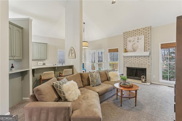 carpeted living room with a brick fireplace and high vaulted ceiling