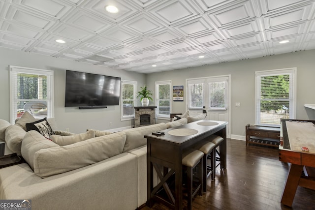 living room with a stone fireplace, dark hardwood / wood-style floors, and a wealth of natural light