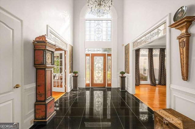 entryway featuring an inviting chandelier and a towering ceiling