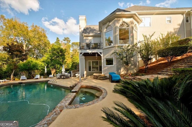 rear view of property with a pool with hot tub, a patio area, and a balcony