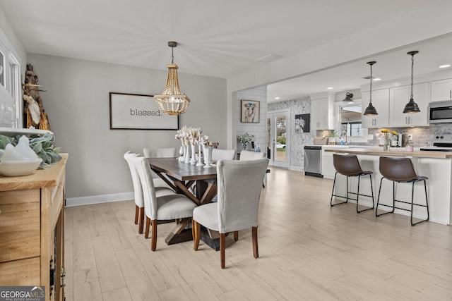 dining area featuring sink, a notable chandelier, and light hardwood / wood-style flooring