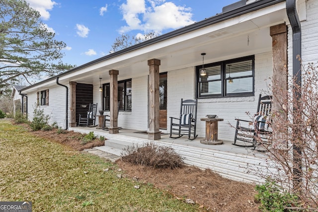 entrance to property with covered porch and a lawn