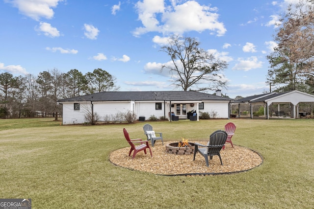 back of house with a fire pit and a lawn