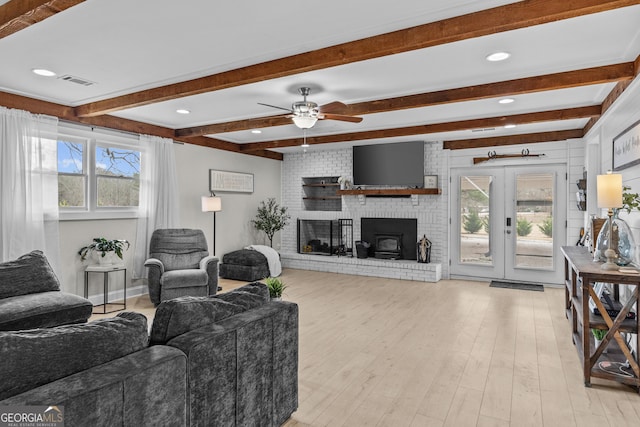 living room featuring french doors, plenty of natural light, beam ceiling, and light wood-type flooring