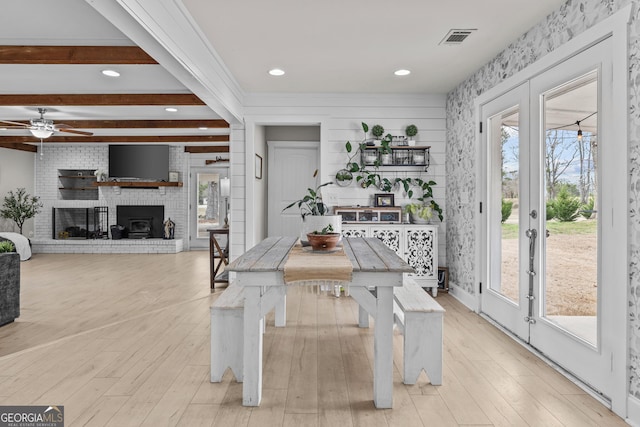 kitchen with a brick fireplace, beam ceiling, light hardwood / wood-style flooring, and french doors