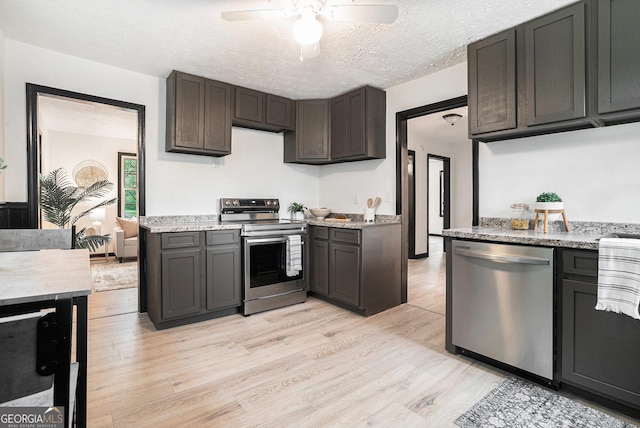 kitchen with light stone counters, a ceiling fan, light wood finished floors, a textured ceiling, and stainless steel appliances