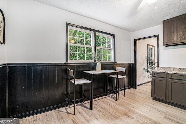 1490 Broad St NE, Conyers, GA 30012 - dining room featuring a wainscoted wall, light wood-type flooring, a textured ceiling, ceiling fan, and wood walls