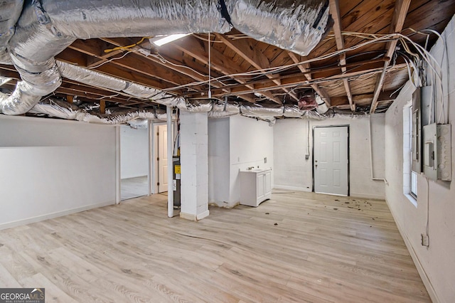 basement with electric panel and light hardwood / wood-style floors